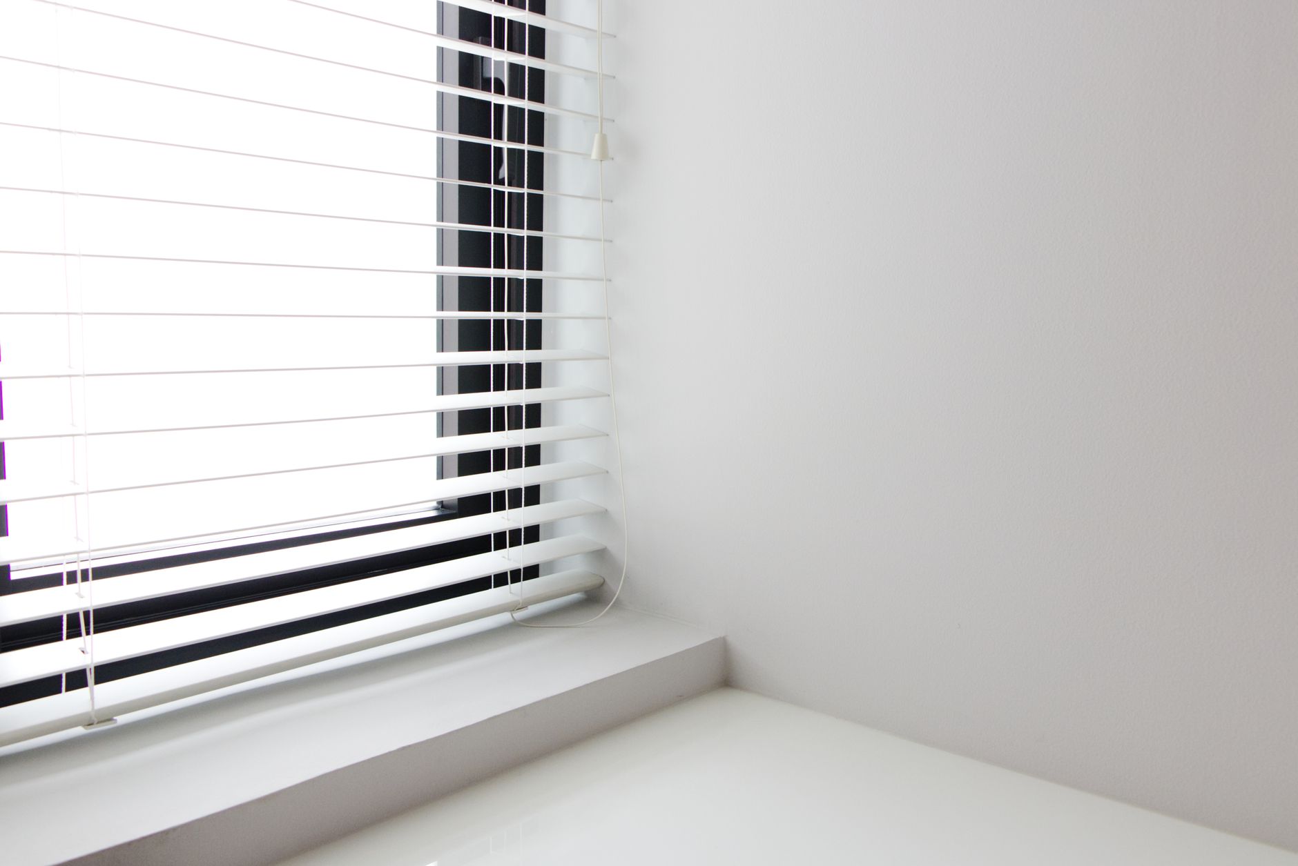 White horizontal blinds fitted neatly at a window